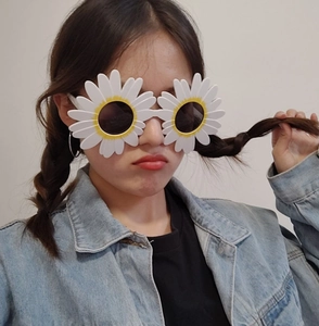Close-up of white daisy fun glasses for parties and selfies worn by a person