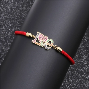 Detailansicht eines roten geflochtenen Armbands mit goldenem LOVE-Herz und Zirkon