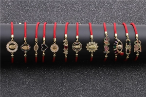 Detailed close-up of red braided bracelets with gold cross and zircon charms on display