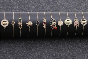 Collection of gold bracelets with colorful charms hanging on a black display stand