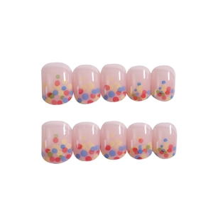 Candy-colored short round press-on nails with playful polka dots on translucent pink base