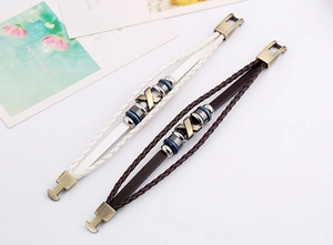Detailed macro shot of vintage woven leather bracelets with bronze X charm and colorful beads
