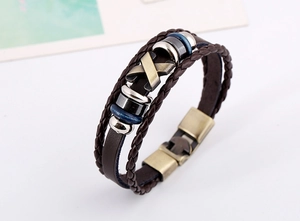 Detail of multi-layer leather bracelet featuring bronze X-shaped metal charm and buckle