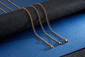 Close-up of golden flat link chains with lobster clasps draped over a black cylinder pedestal