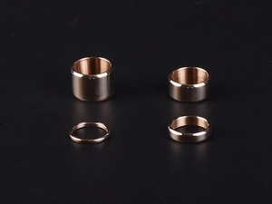 Polished rose gold titanium steel rings in wide and narrow bands on a black background