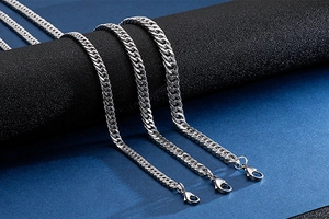 Three silver stainless steel Cuban link necklaces with lobster clasps on a display