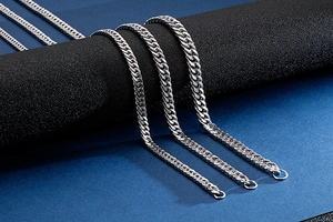 Close-up of silver stainless steel curb link necklaces on black display stand