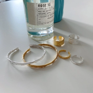 Close-up of S925 silver rings and bracelets featuring hammered texture and gold foil finish