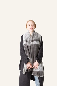 Detail of soft grey plaid scarf featuring warm bouclé texture and delicate tassel fringe