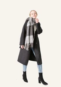 Detailed view of black and white plaid scarf with fringe tassels on a black coat