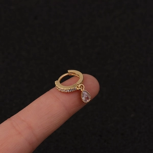 Macro shot of gold hoop earring with drop charm and inlaid zircon on black background