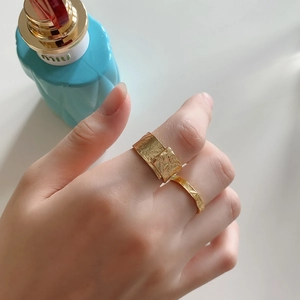 Detail of minimalist gold irregular lava texture and hammered open rings on hand