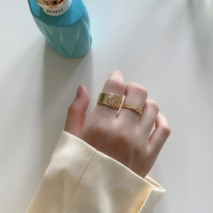 Macro detail of gold textured rings with irregular hammered finish on model hand