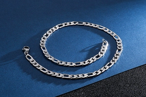 Detail of 9mm stainless steel Figaro link chain with secure lobster clasp on dark background