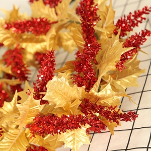 Christmas wreath decoration with golden artificial leaves and red glitter berries on fabric