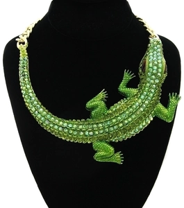 Macro detail of a large vintage crocodile necklace with green rhinestones on gold chain