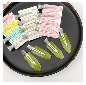 Macro shot of colorful glitter hair clips in various pastel shades inside a black tray