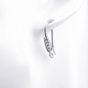 Macro detail of silver earring hook with zircon inlay on model ear for DIY jewelry