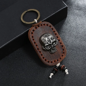 Handmade vintage leather keychain with skull emblem and bronze ring on black background