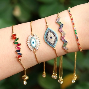 Rainbow evil eye bracelets in gold with colorful zircons worn on arm in nature
