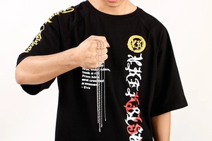 Détail d'un collier chaîne à billes en acier inoxydable porté sur un T-shirt noir