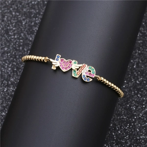 Gold LOVE chain bracelet with colorful zircon heart and palm charms on a black display