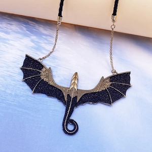Close-up of vintage gold dragon pendant with detailed wings on black cord necklace