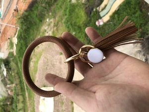 Close-up of brown litchi pattern leather wristlet keychain with gold ring and tassel