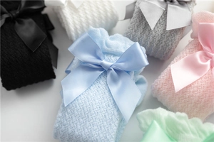 Close-up of children's mesh socks with satin bows in various pastel colors and textures