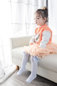 Close-up of light blue mesh knee-high socks for kids with elegant silk bow decoration