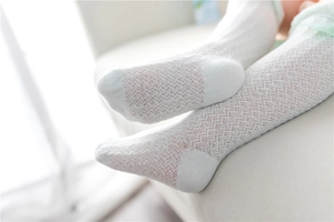 Close-up of white lace mesh baby socks showing breathable hollow patterns and texture