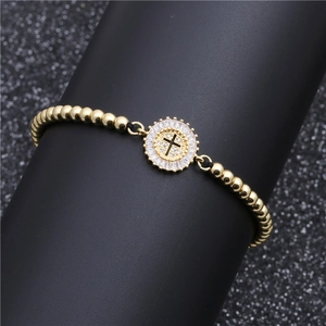 Adjustable gold beaded bracelet featuring a round cross pendant with cubic zirconia inlay