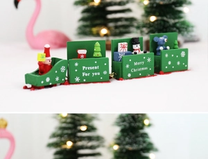 Detailed view of green wooden Christmas train with Santa and gift miniatures on snow