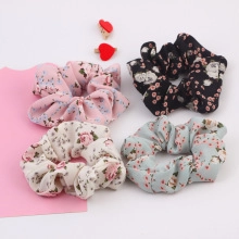 Detailed view of four floral print scrunchies in pink, black, white, and blue fabric