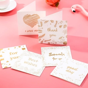 Close-up of elegant white gift cards with gold foil lettering on a stylish pink background