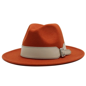 Detail of burnt orange fedora hat featuring wide brim and white leather belt with silver buckle