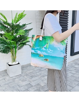 Detail of tropical beach landscape printed tote bag with white rope handles on shoulder
