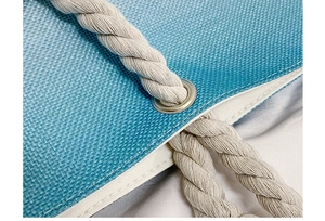 Detail of blue canvas beach bag featuring sturdy rope handle and metal eyelet reinforcement