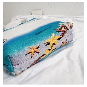 Detail of beach canvas tote featuring starfish patterns and white tassel trim accents