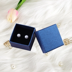 Detail of elegant white pearl earrings in a dark blue textured jewelry gift box
