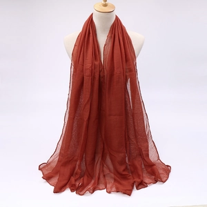 Detail of candy-colored voile scarf in caramel red showing breathable texture and drape