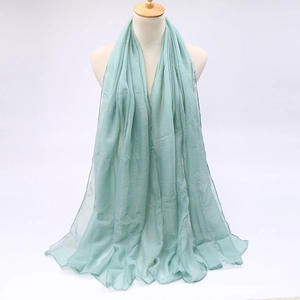 Detail of mint green sun protection scarf with lightweight pleated texture hanging on a stand