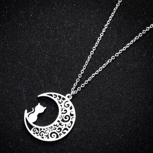 Detail of silver cat sitting on crescent moon pendant with hollow floral pattern