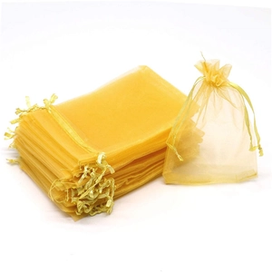 Macro detail of golden organza gift bags with drawstring closure for Christmas favors