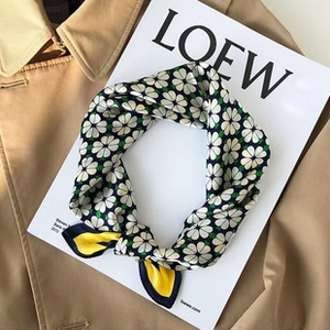 Detailed view of floral silk scarf on magazine and trench coat for stylish summer look