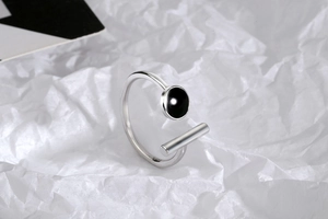 Close-up of minimalist silver open ring with black round enamel and geometric bar detail