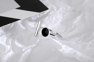Detail of silver open ring with black round stone and bar on geometric background