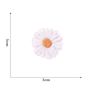 Macro detail of a 3cm white and orange daisy embroidered patch with needlework texture
