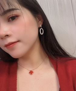 Detail of model wearing red clover pendant necklace and sparkling teardrop earrings