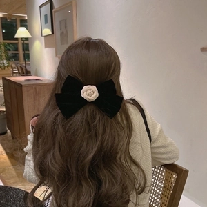 Barrette à cheveux élégante en velours noir avec camélia portée par le modèle